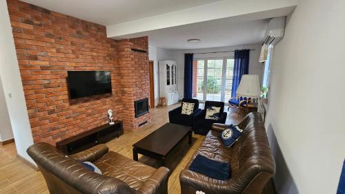 a living room with leather furniture and a brick wall at Dom u Kapitana w Lubiatowie in Lubiatowo