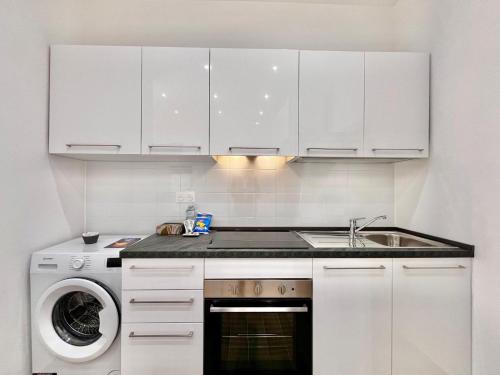 une cuisine blanche avec un évier et un lave-vaisselle dans l'établissement Jardin Bleu - Menton centro, à Menton