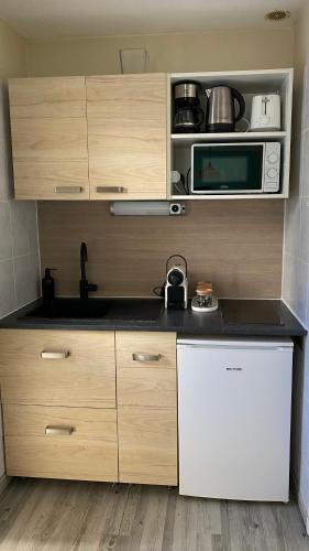 La cuisine est équipée d'un réfrigérateur blanc et d'un four micro-ondes. dans l'établissement Appartement bord de mer Palavas, à Palavas-les-Flots