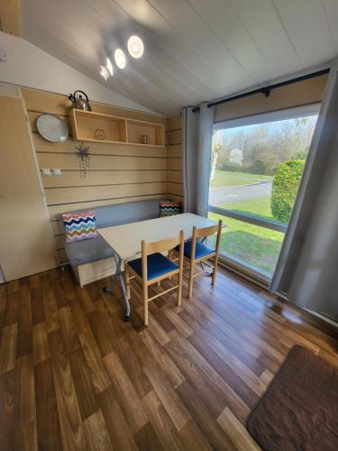 a room with a table and chairs and a window at "Les pieds dans l'Orne" - Mobil home 5 personnes in Ouistreham