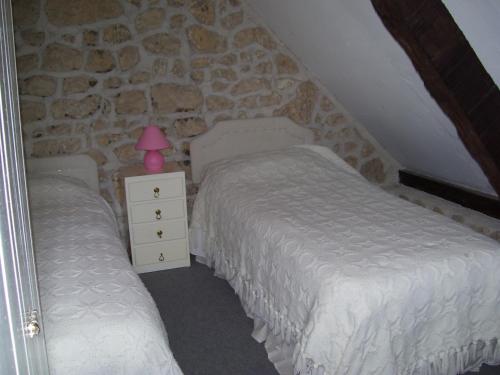 - une chambre avec 2 lits et une lampe rose sur une commode dans l'établissement la Laverie, à Allonnes