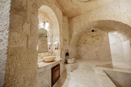 a stone bathroom with a tub and a sink at Kemerhan Cave Suites in Urgup
