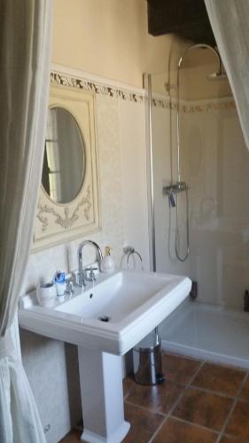 une salle de bain blanche avec un lavabo et une douche dans l'établissement La Maison aux Volets Bleus, à Saint-Clément