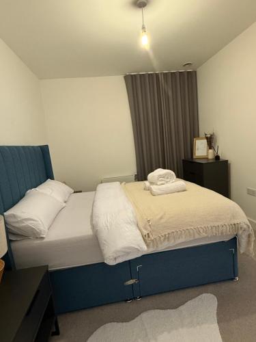 a bedroom with a bed with a blue headboard at Dynamic Luxury Apartment in Barking