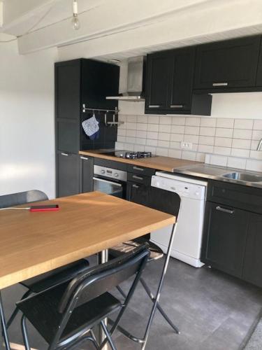 une cuisine avec des armoires noires et une table en bois dans l'établissement Gite Mer & Vallons à proximité plage des Grands Sables, à Locmaria