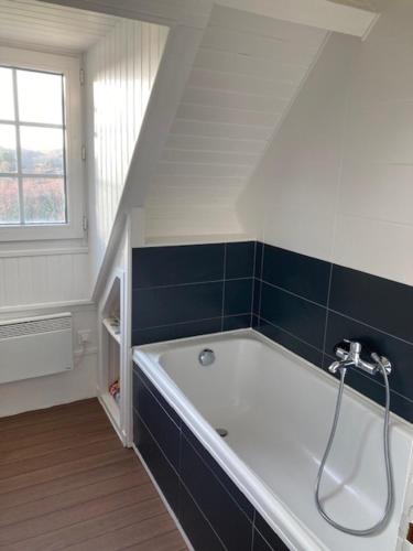 La salle de bains est pourvue d'une baignoire avec du carrelage bleu. dans l'établissement Gite Mer & Vallons à proximité plage des Grands Sables, à Locmaria