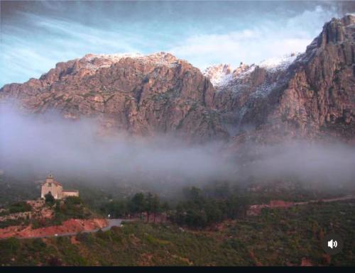 a mountain range with a church in the clouds at Casa Añeja in Collbató