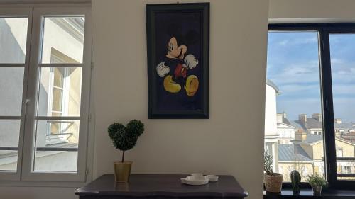 a table with a picture on the wall next to a window at VERY CENTRAL DISNEYLAND apartment in Serris