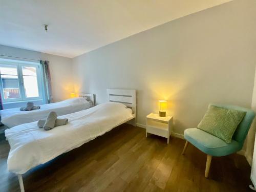 une chambre d'hôtel avec deux lits et une chaise dans l'établissement Le Duplex Géromois, beautiful apartment & city center, à Gérardmer