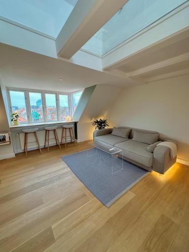 a living room with a couch and some windows at Central rooftop apartment by ARoS with balcony in Aarhus