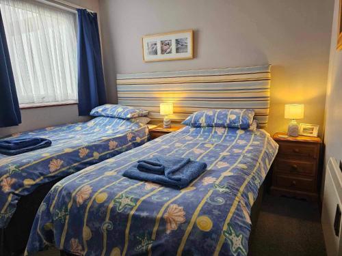 ein Schlafzimmer mit zwei Betten mit blauen Handtüchern darauf in der Unterkunft Waterside Holiday Cottage on Camel Trail Wadebridge Sleeps 5 in Wadebridge