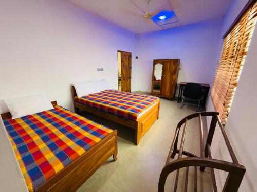 a room with two beds and a chair in it at Birds Nest in Trincomalee