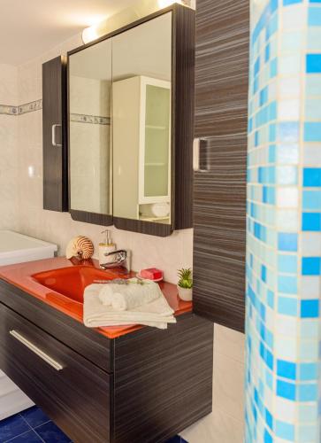 a bathroom with a red sink and a mirror at Sea Lullaby in Drymonas
