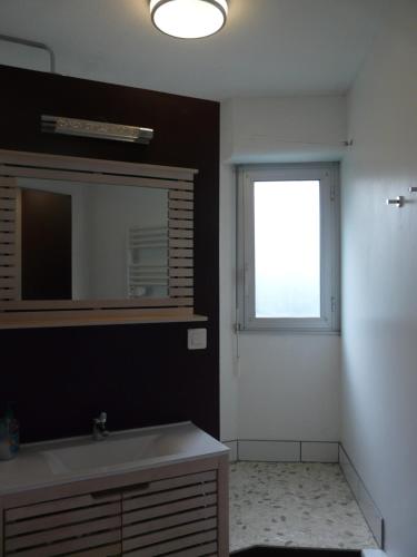 une salle de bain avec un lavabo, un miroir et une fenêtre dans l'établissement Arcachon Pereire bord de plage, à Arcachon