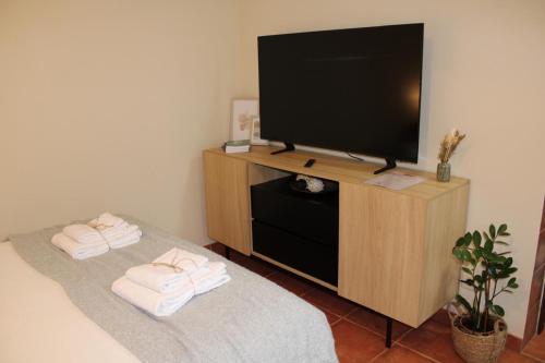 a flat screen tv sitting on a wooden stand with towels at Carmo guestroom in Tabuaço