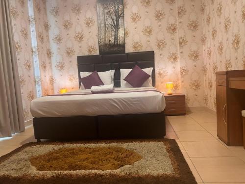 a bedroom with a large bed with purple pillows at Desert Pearl Hotel Apartment in Manama