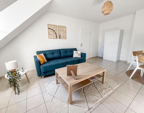 un salon avec un canapé bleu et une table dans l'établissement FairyHome Parking Privé Proche Disney, à Magny-le-Hongre