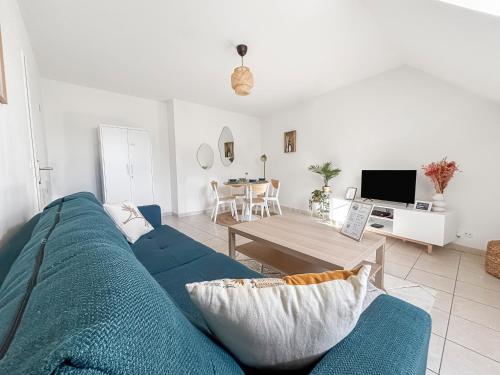 un salon avec un canapé bleu et une table dans l'établissement FairyHome Parking Privé Proche Disney, à Magny-le-Hongre