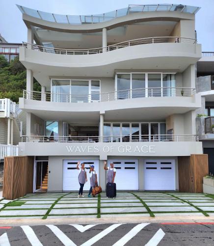 three people standing in front of a building at Waves of Grace Seafront Villa in Herolds Bay