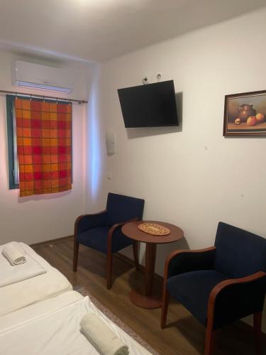 a room with two chairs and a table and a tv at Turul Panzió&Pizzéria in Szólád