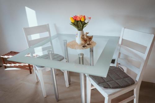 a glass table with a vase of flowers and two chairs at Little Break in Röfingen