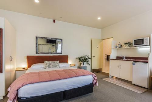 a bedroom with a large bed and a kitchen at Boutique Motel in Nelson