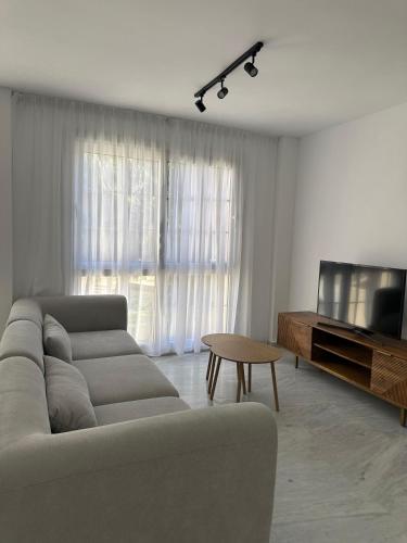 a living room with a couch and a tv and a table at Sol Puerto Apartamento en Almerimar in Almerimar