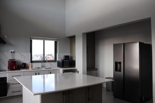 a kitchen with a stainless steel refrigerator and a window at Ocean Bliss Penthouse - Private Pool & 2 Min to Beach in Flic-en-Flac
