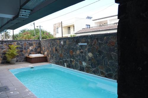 a swimming pool with a stone wall next to a building at Ocean Bliss Penthouse - Private Pool & 2 Min to Beach in Flic-en-Flac