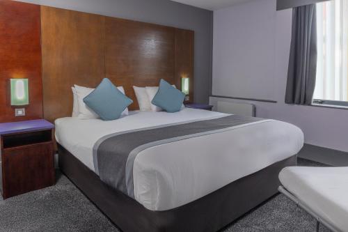 a bedroom with a large bed with blue pillows at Best Western Sheffield City Hotel in Sheffield