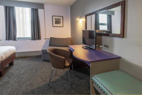 a hotel room with a desk with a television and a couch at Best Western Sheffield City Hotel in Sheffield