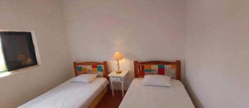 two beds in a room with a lamp on a table at Casa da Corte in Mina de São Domingos