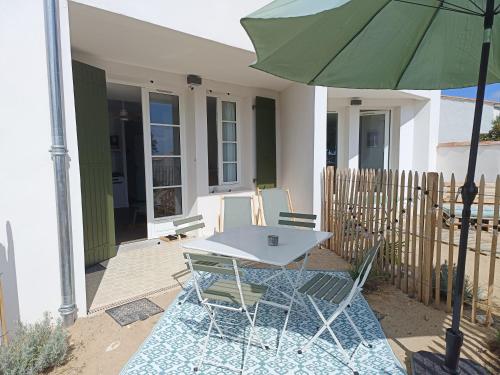 a table and chairs under an umbrella on a patio at La Plage, T2 vue mer in Rivedoux-Plage