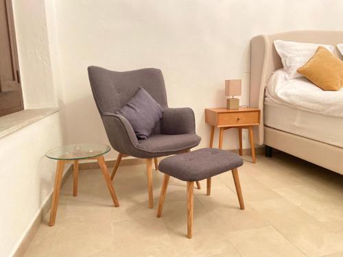a chair and stool in a room with a bed at Depandance Eleonora in Oristano