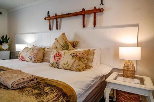 a bedroom with a bed and a table with a lamp at The Hedge Cottage in Riebeek-Kasteel