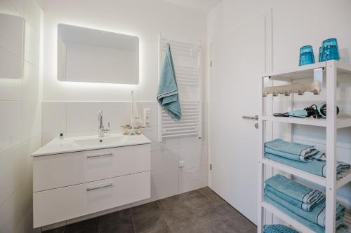 une salle de bain blanche avec un lavabo et un miroir dans l'établissement Ferienhaus Dorfkiek - Bauernhof Hopp Vadersdorf, à Fehmarn