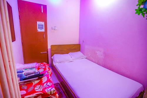 a small room with a bed and a red door at Hotel Padma Dhaka in Dhaka