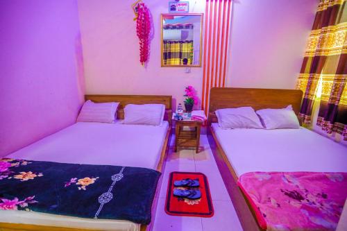 a room with two beds and a table with a mirror at Hotel Padma Dhaka in Dhaka