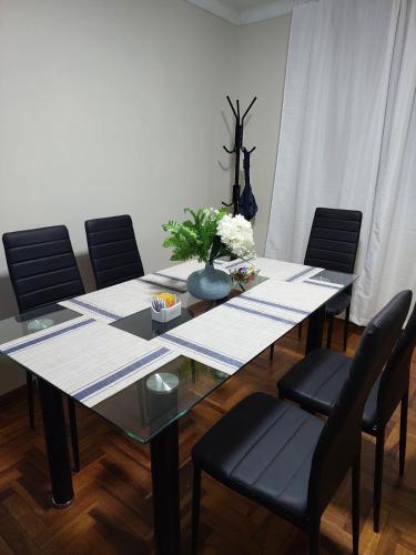 a dining table with chairs and a vase of flowers on it at JTM Apartament in Cusco