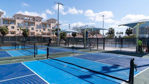 a tennis court with two tennis nets and umbrellas at Jade House at The Gemma in Clearwater Beach