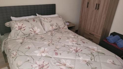 a bed with a white comforter with pink flowers on it at JTM Apartament in Cusco