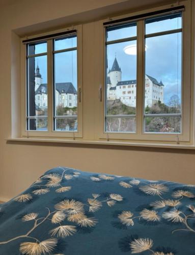 Villa Schlossblick في Neuanbau: سرير مع لحاف أزرق في غرفة نوم مع نوافذ