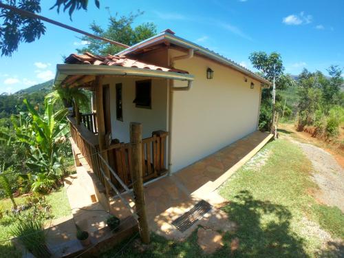 a small house with a porch next to a yard at Chalé Biribó in Conceição do Mato Dentro