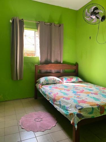 a green bedroom with a bed and a fan at Pousada Luz do Sol in Algodoal