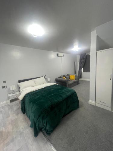 a bedroom with a large bed and a couch at Cozy Studio Flat Romford, London in Romford