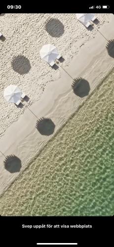 a beach with umbrellas and footprints in the sand at Apartman Celine PortoNovi in Kumbor