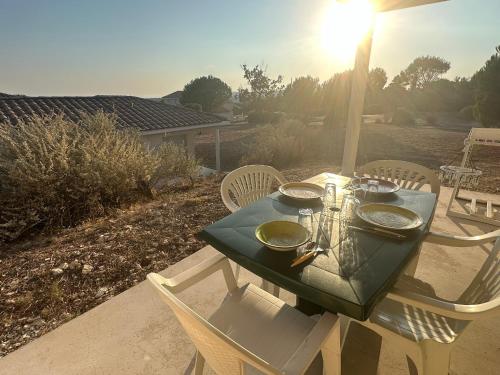 a table and chairs with a green table and the sun at Villa le Castellet et proche circuit Paul-Ricard à 20 mn de la Mer in Signes
