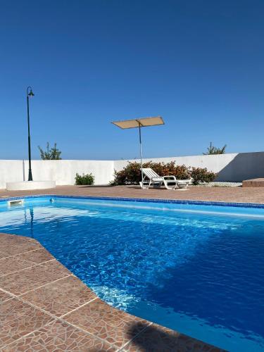a blue swimming pool with a chair and an umbrella at Monte Açores in Ferreira do Alentejo