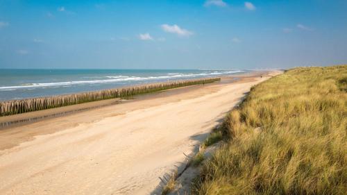 a sandy beach next to the ocean with a fence at Maison proche de la plage et du CNPE in Oye-Plage