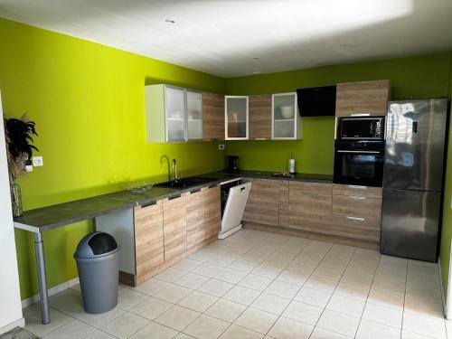 a kitchen with green walls and wooden cabinets at Maison proche de la plage et du CNPE in Oye-Plage